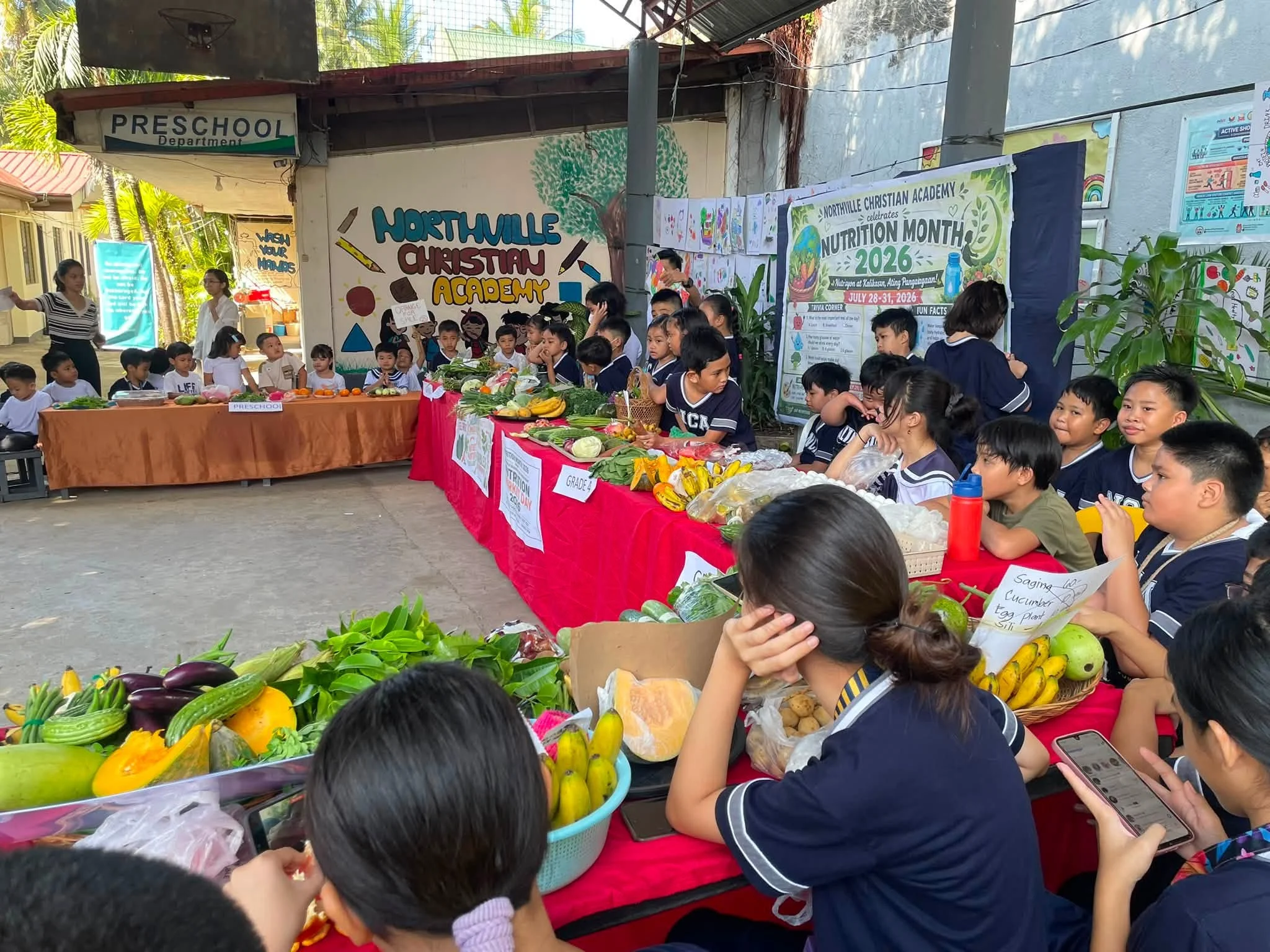 A produce display for Nutrition Month sits outside a building with a "Preschool" sign.