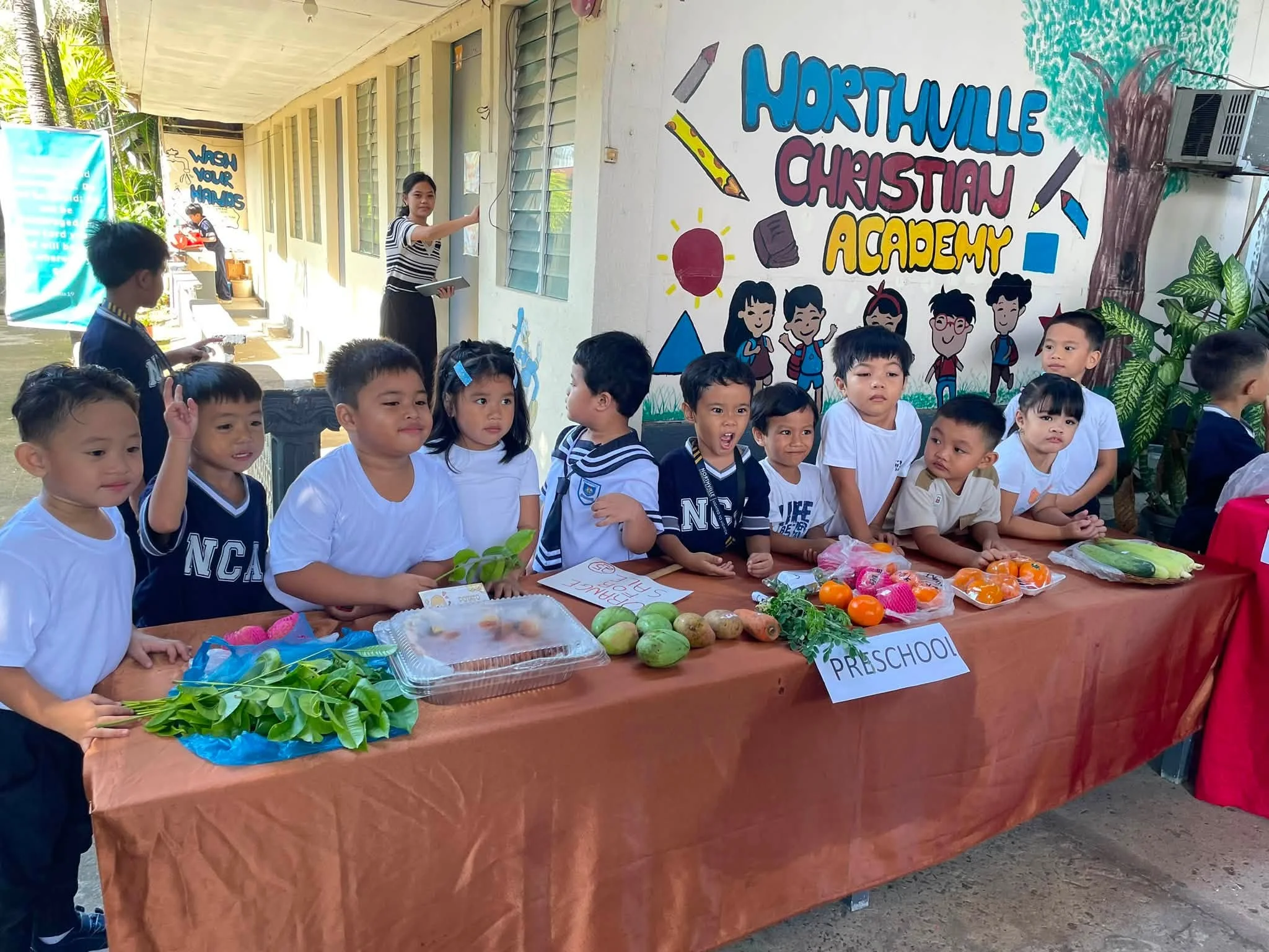 Children stand in front of a wall hand-painted with the words "Northville Christian Academy."